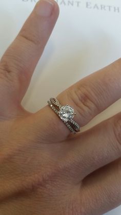 a woman's hand with a diamond ring on top of her wedding band and an engagement ring in the middle