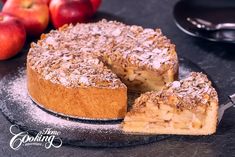 a cake on a plate with one slice cut out and some apples in the background