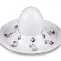 an egg sitting on top of a white saucer with pink and blue birds painted on it