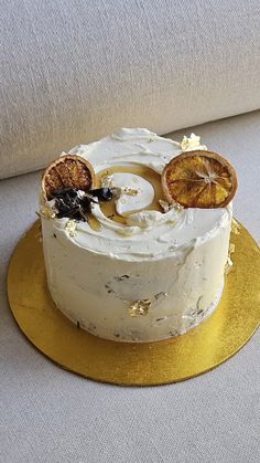 a cake with white frosting and oranges on top sitting on a gold plate