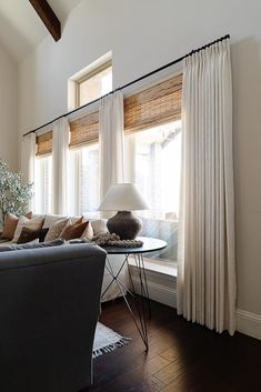 a living room filled with furniture and a window covered in white drapes next to a lamp