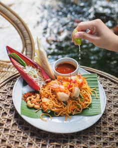 someone is dipping sauce on some noodles with shrimp and other food items in the bowl