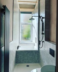 a bathroom with a window, sink and toilet in the shower stall next to it