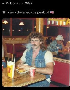 a man sitting at a table with a hot dog in front of him