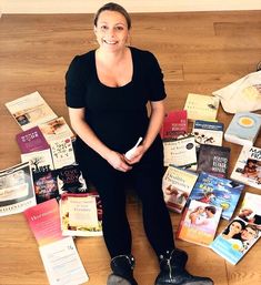 a woman sitting on the floor surrounded by books