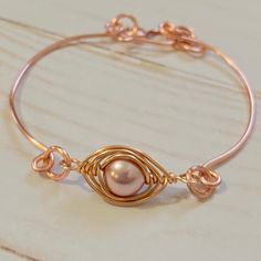 "This gorgeous Rose Gold Pearl Bangle is a unique piece that will increase your beauty anytime you wear it.  It's made from gold plated wire and a rose tone pearl bead that is delicately wrapped with wire.  ITEM-DETAILS: Materials: Rose Gold Plated Wire, Pearl Bead.  Length: 6.5 inches  Turquoise Bead: 0.5 inches Thank you for visiting my product. You can see more amazing designs in my shop clicking here: https://www.etsy.com/shop/NanisInspiration Share your pictures with me and get inspired wit Elegant Hand Wrapped Rose Gold Bracelet, Rose Gold Pearl Jewelry With Wire Wrapped Detail, Handmade Rose Gold Pearl Bracelet Gift, Rose Gold Bangle Pearl Bracelet As A Gift, Rose Gold Wire Wrapped Bracelet, Adjustable Handmade Rose Gold Pearl Bracelet, Wire Wrapped Rose Gold Bracelet, Handmade Rose Gold Pearl Bracelet, Adjustable Rose Gold Wire Wrapped Bracelets