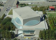 an aerial view of a large building in the middle of a parking lot with lots of trees around it