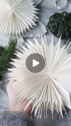 someone is holding an origami fan in their hand, surrounded by other paper decorations