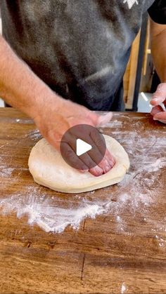 a person kneading dough on top of a wooden table