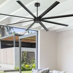 a living room with a white couch and black ceiling fan in front of a sliding glass door