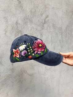 a person is holding up a hat with flowers painted on the front and side of it