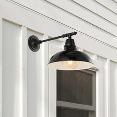 an outdoor light is mounted on the side of a house with white siding and windows