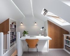 a room with a desk, bookshelf and stairs leading to the top floor