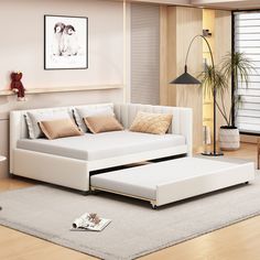 a living room with a white couch and ottoman in the middle, on top of a rug