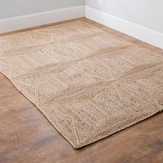 an area rug on the floor in a room with wood floors and white wall paint