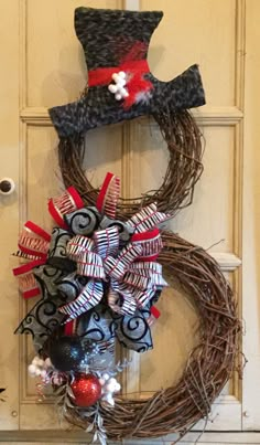 a wreath with a top hat and ornaments hanging from it's side on a door