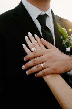 the bride and groom are holding each other's hands with wedding rings on their fingers