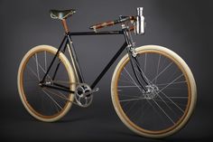 a black and brown bike with wooden spokes on it's front wheel, against a dark background