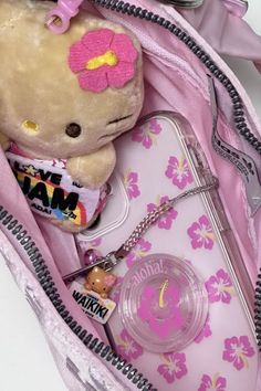 a hello kitty doll in a pink purse with some keys and other items inside it