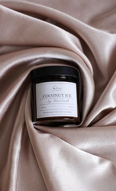 a jar of coconut ice sitting on top of a satin fabric