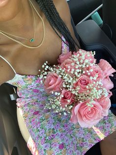 a woman sitting in a car holding a bouquet of pink roses and baby's breath