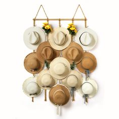 several hats hanging on a wall with flowers in the center and two hooks holding them