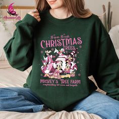 a woman wearing a green christmas sweatshirt with mickey and minnie on it