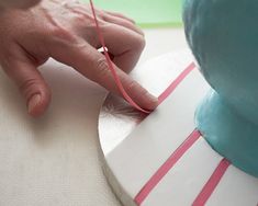 a person is decorating a cake with pink and white stripes