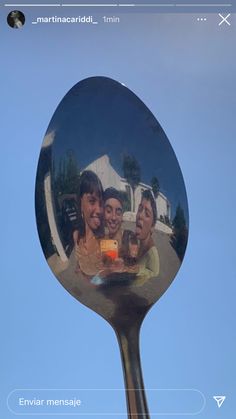 the reflection of three people in a mirror is shown on a spoon with blue sky behind it