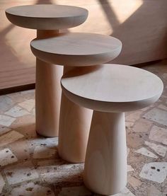 three wooden stools sitting on top of a tiled floor