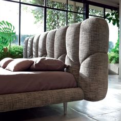 a bed that has some pillows on top of it in front of a large window