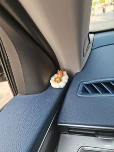 a car dashboard with a small white flower on the center console and blue dash mat