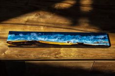 a wooden table topped with a blue and yellow piece of art on top of it