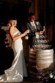 a bride and groom are standing next to a wine barrel with a cake on it