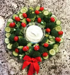 a platter filled with cucumbers, tomatoes and broccoli topped with ranch dressing