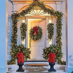 christmas wreaths on the front door of a house decorated with lights and greenery