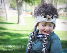 a young boy wearing a crocheted hat with an animal on it's head