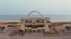 an aerial view of a large building with a huge arch in the center and some stairs leading up to it