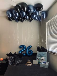 balloons are hanging from the ceiling above a table with a cake and other items on it