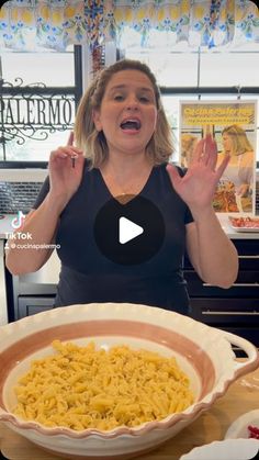 a woman standing in front of a bowl filled with macaroni and cheese