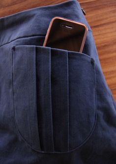 a cell phone sticking out of the pocket of a blue bag on top of a wooden floor