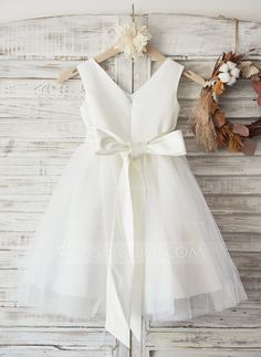 a white dress hanging on a wooden wall next to a wreath and dried flower headband