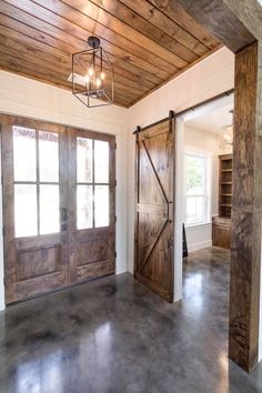 an empty room with two wooden doors and a chandelier hanging from the ceiling