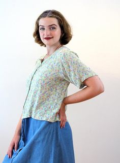 This is a sweet 90s vintage Indonesian blouse in a pastel, light mint green with a cute flower print in blue, coral, yellow and dark green. The fabric is gauze rayon, very soft to touch, with a crinkly texture. The blouse has half length sleeves, a scoop neckline, a boxy shape with no darts and a straight hem. It closes with four pale green buttons in the front.The top is in good clean, freshly laundered vintage condition with a top button missing at the neckline. The label says "M, Banyan Tree, Vintage V-neck Blouse In Relaxed Fit, Vintage V-neck Blouse With Relaxed Fit, Vintage Relaxed Fit V-neck Blouse, Cottagecore Spring Top With Buttons, Vintage Floral Print Relaxed Fit Blouse, Retro Summer Blouse With Button Closure, Vintage Blouse With Relaxed Fit For Spring, Vintage Button-up Summer Blouse, Vintage Summer Blouse With Buttons