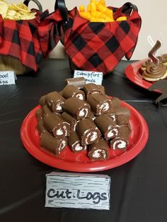 a red plate topped with lots of chocolate covered pastries next to other desserts