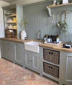 a kitchen with gray cabinets and wooden counter tops, white sink and dishwasher