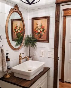 a bathroom sink sitting under a mirror next to a wooden counter topped with a potted plant