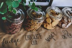 four glass jars filled with different types of cookies