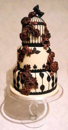 a three tiered cake decorated with flowers and birdscage