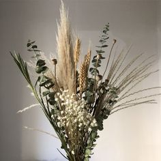 a vase filled with lots of white flowers and greenery on top of a table